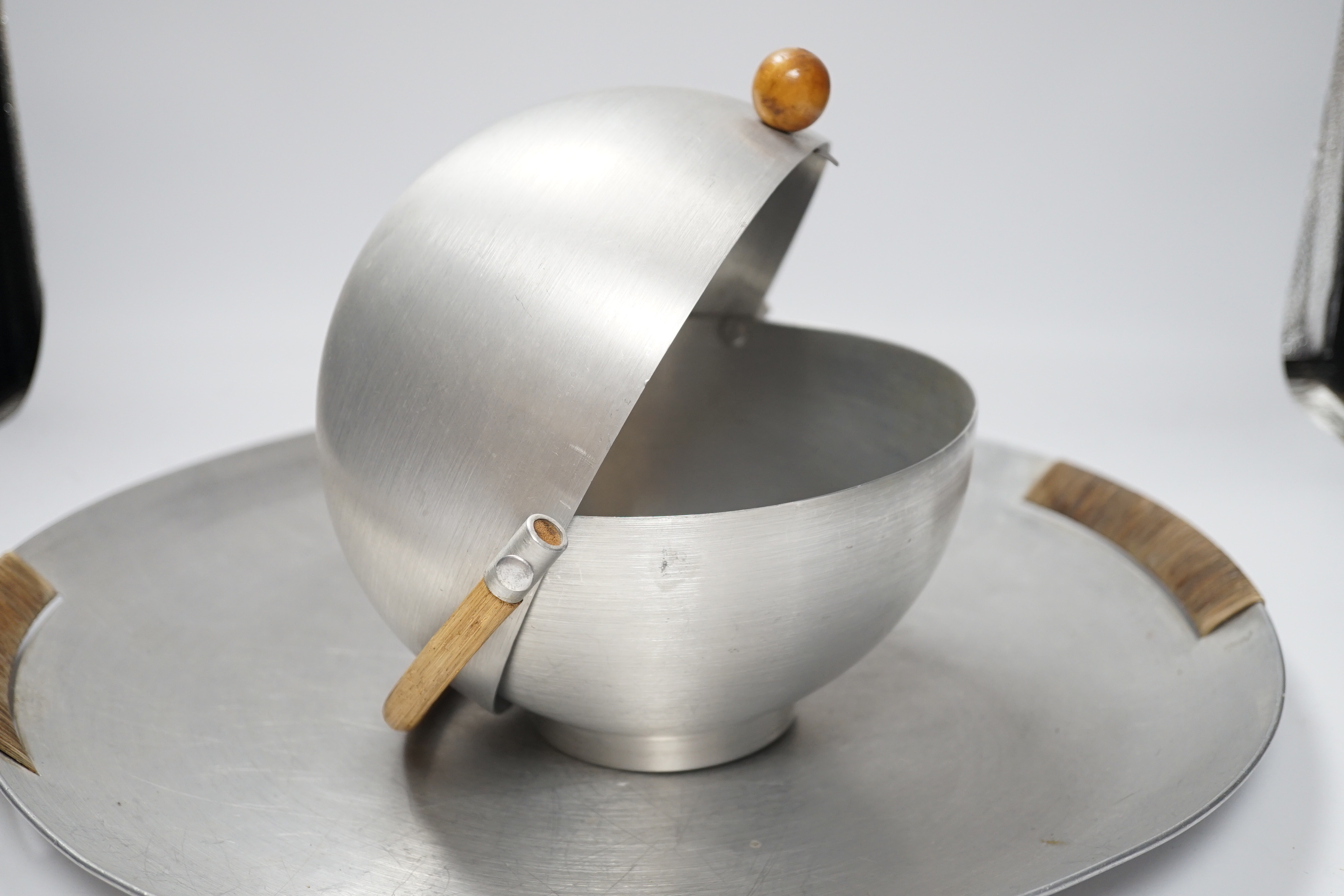 A Russell Wright spun aluminium ‘bun’ warmer and tray with woven handles, largest 45cm in diameter